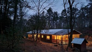 Una cabana amb façana de fusta, diverses finestres i un petit cobert adjacent.