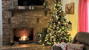 Un saló acollidor amb una llar de pedra, un arbre de Nadal i un sofà confortable.