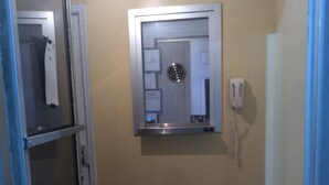 A narrow hallway with a door on the right, a phone on the wall, and a door on the left. - Richmond Motel (Richmond)