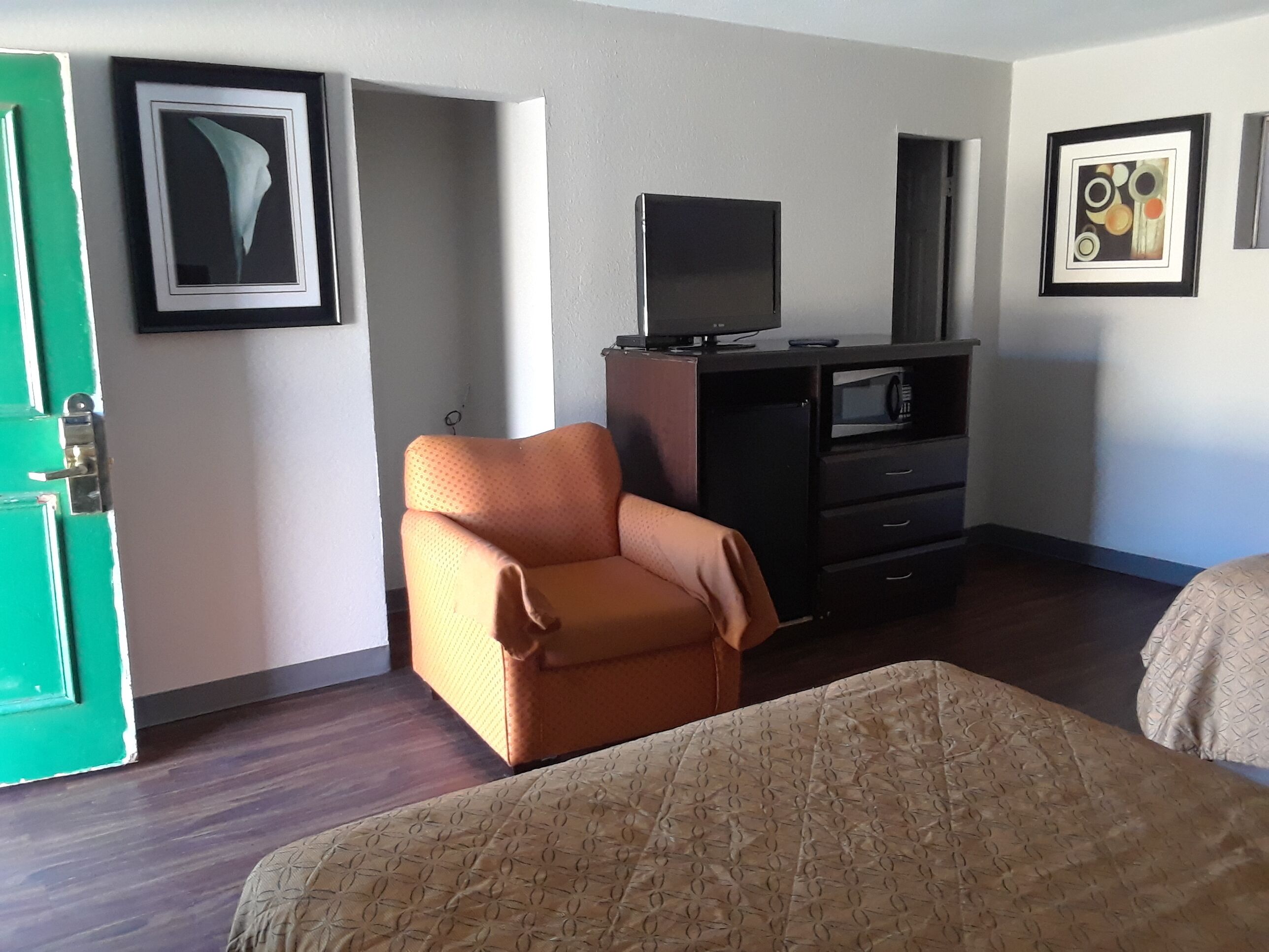 A hotel room with a bed, a chair, a TV, and a microwave.