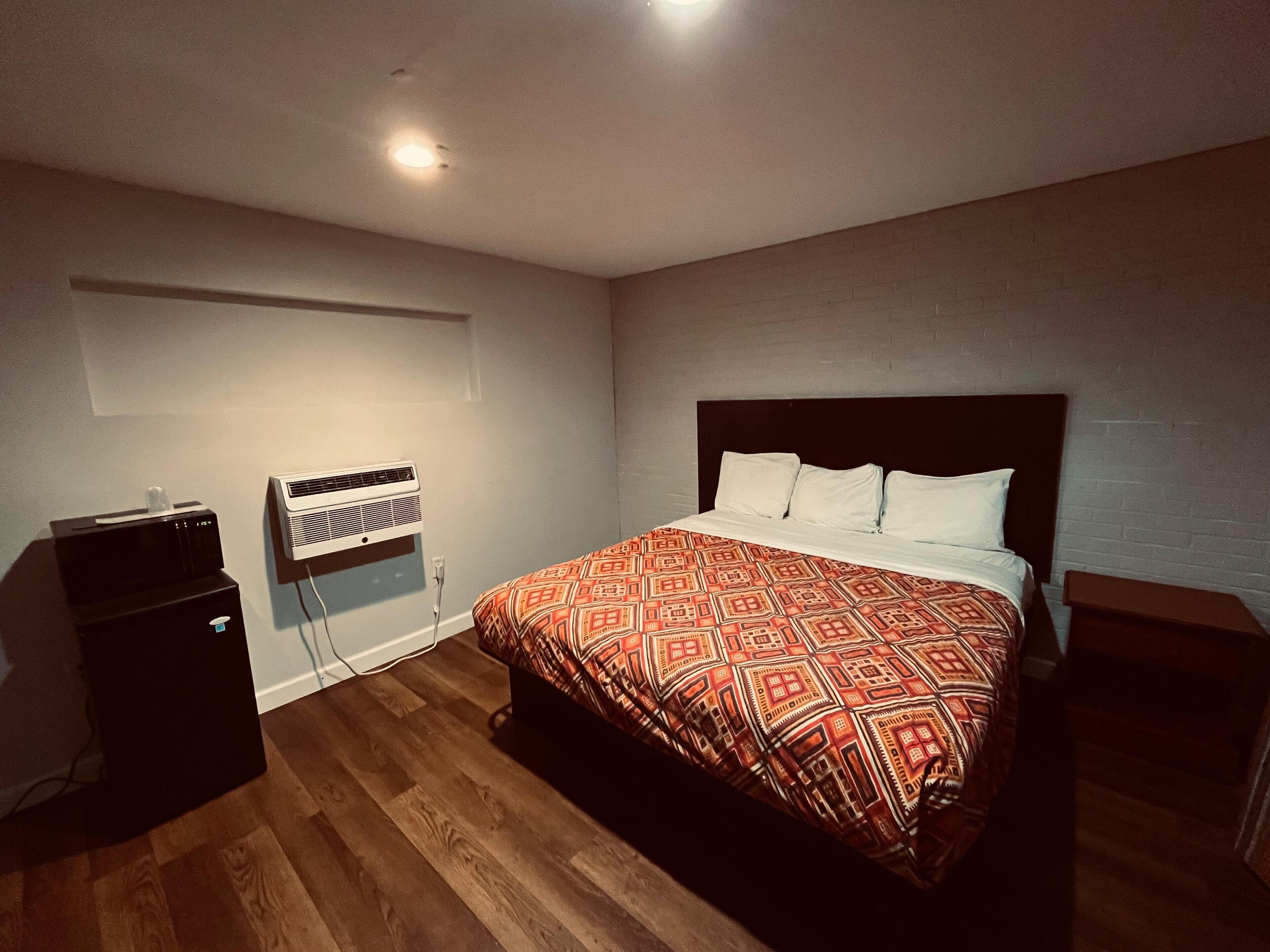 Een slaapkamer met een bed, een nachtkastje, een verwarming en een klein kastje.
