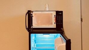 A compact refrigerator with a digital display, a microwave on top, and a freezer compartment. - Richmond Motel (Richmond)
