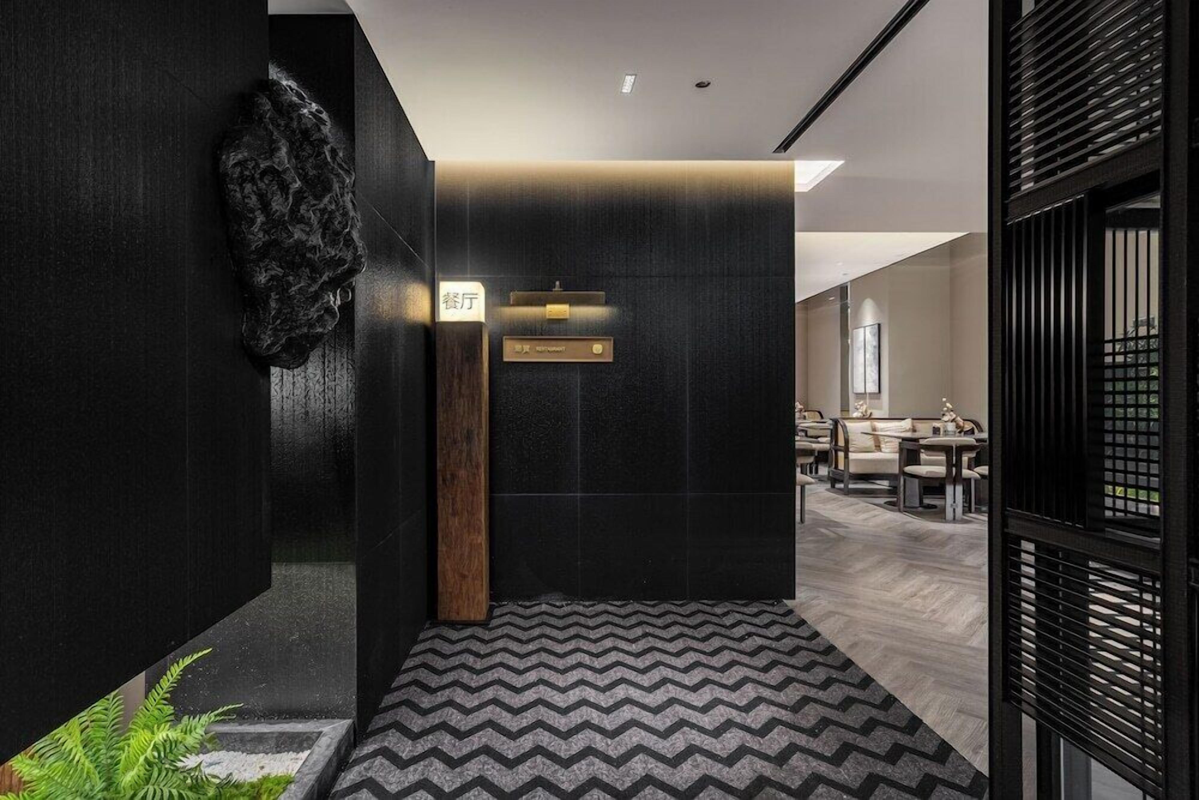 A modern hotel lobby with a reception desk, seating area, and a decorative wall.