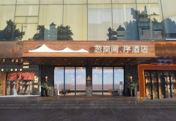 A hotel entrance with a wooden sign, large glass doors, and a view of the surrounding area. - Borrman Hotel (Guangzhou Tianhe Sports Center Linhe West Metro Station) (Guangzhou)