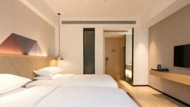 A modern hotel room with a large bed, a TV mounted on the wall, and a door leading to another room. - Borrman Hotel (Guangzhou Tianhe Sports Center Linhe West Metro Station) (Guangzhou)
