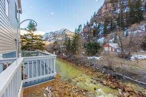 A river flowing through a mountainous area with a house and a red building in the background. - River Views | Next to Ouray Hot Springs | Walk to Restaurants (Ouray)