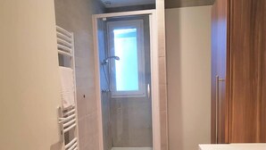 Een kleine, moderne badkamer met een douche, toilet en een witte wasbak.