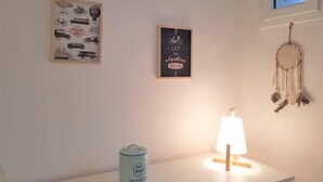 Een kamer met een witte muur, een lijst met afbeeldingen van klassieke voertuigen, een motiverende quote, een dromenvanger, een lamp en een suikerpot.
