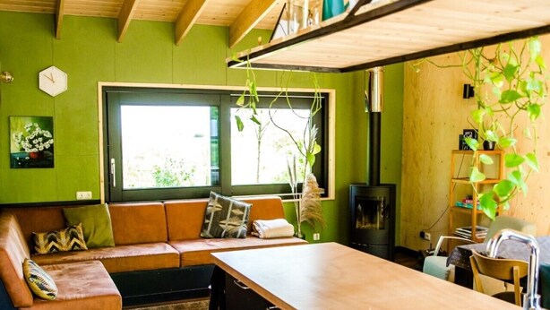 A modern kitchen with wooden beams, a built-in bench, and a large window. - Nature lodge Ljip, Akkrum - sleeps 6 by the water (Akkrum)
