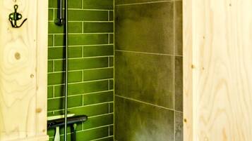 Een douche met een wand betegeld met groene tegels en een houten deur.