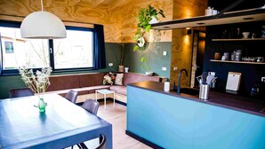 A modern kitchen with a blue countertop, wooden ceiling, and a hanging plant.