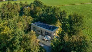 Ein modernes Haus mit einer Solardach, umgeben von üppigem Grün und einem See.