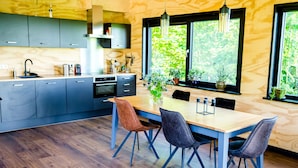Eine moderne Küche mit grauen Schränken, einer Holzarbeitsplatte und einem Essbereich mit Holztisch und -stühlen.