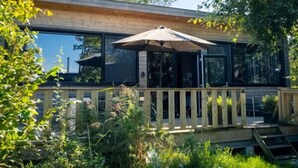 A modern house with a deck, large windows, and a wooden fence. - Nature lodge Reade Wikel, Akkrum - children`s sleeping hut (Akkrum)