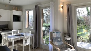 A modern kitchen with white cabinets, a microwave, and a dining area with white chairs and a table.