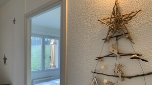 A bedroom with a bed, a star decoration on the wall, and a Christmas tree made of branches and ornaments.