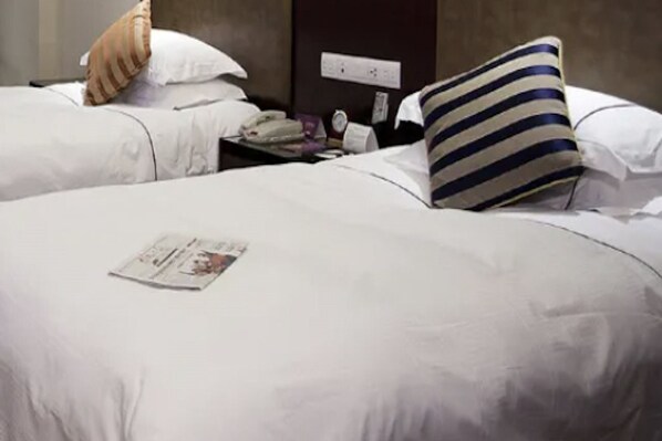A hotel room with two beds, each with white bedding and striped pillows. A newspaper is placed on the bed in the foreground. - Haiyan International Hotel (Jiaxing)