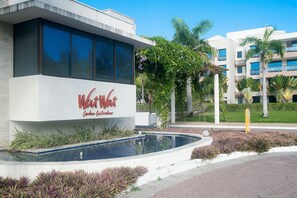 A hotel entrance with a pool, palm trees, and a sign that reads "Walt's."