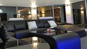 Ein modernes Wohnzimmer mit einer großen Eckcouch, einem Glastisch und einer einzigartigen runden Deckenleuchte.