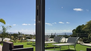 Eine Terrasse mit Sitzgelegenheiten im Freien, Blick auf das Meer und einem klaren Himmel.