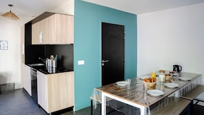 Een moderne keuken met een zwart aanrecht, houten kastjes en een wand in teal.