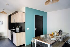 Een moderne keuken met een zwart aanrecht, houten kastjes en een wand in teal.