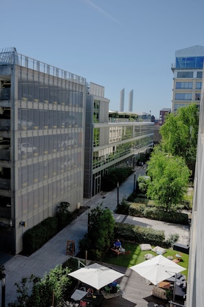 Un edificio moderno con un espacio exterior cubierto, que incluye asientos y sombrillas.