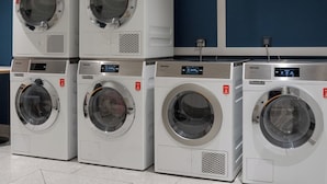 Een wasserette met meerdere gestapelde wasmachines en een technische muur.