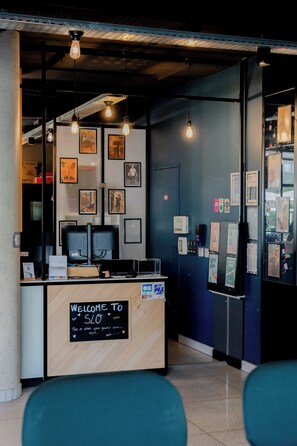 A reception desk with a sign reading 'Welcome to SLO,' a computer, framed pictures on the wall, and a blue wall with various notices.
