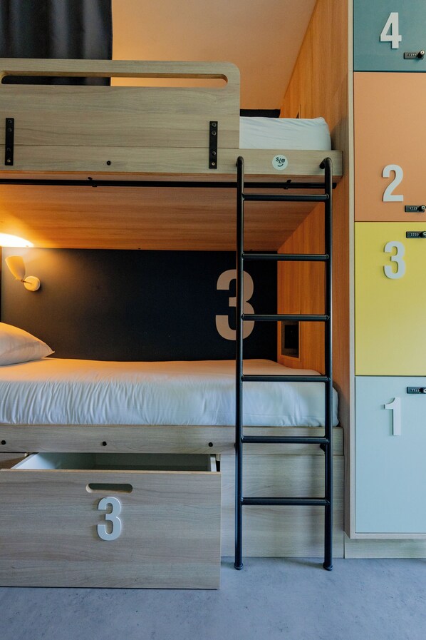 Ein Stockbett mit einer Leiter, ein Nachttisch und ein Kleiderschrank mit nummerierten Fächern.