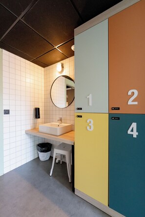 A restroom with a sink, mirror, and numbered lockers.
