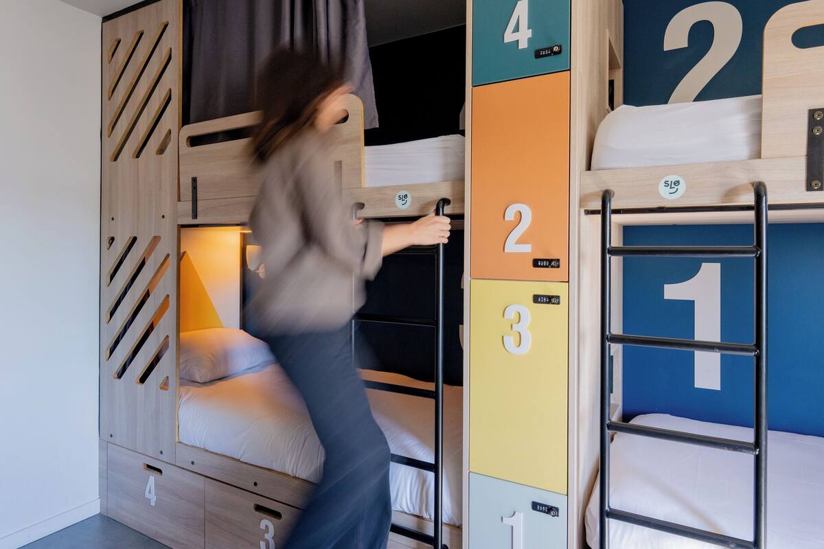 Une chambre avec un lit superposé, un placard intégré et une échelle.