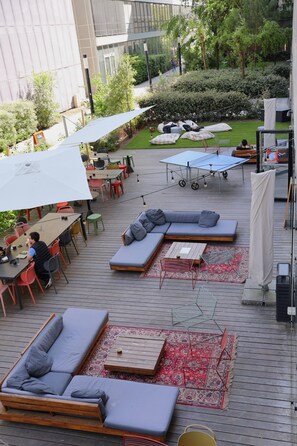 Ein Patio mit Sitzgelegenheiten, Tischen und Sonnenschirmen.