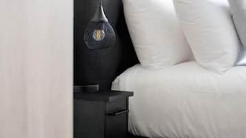 Un lit avec une literie blanche, une tête de lit sombre et une lampe de chevet.