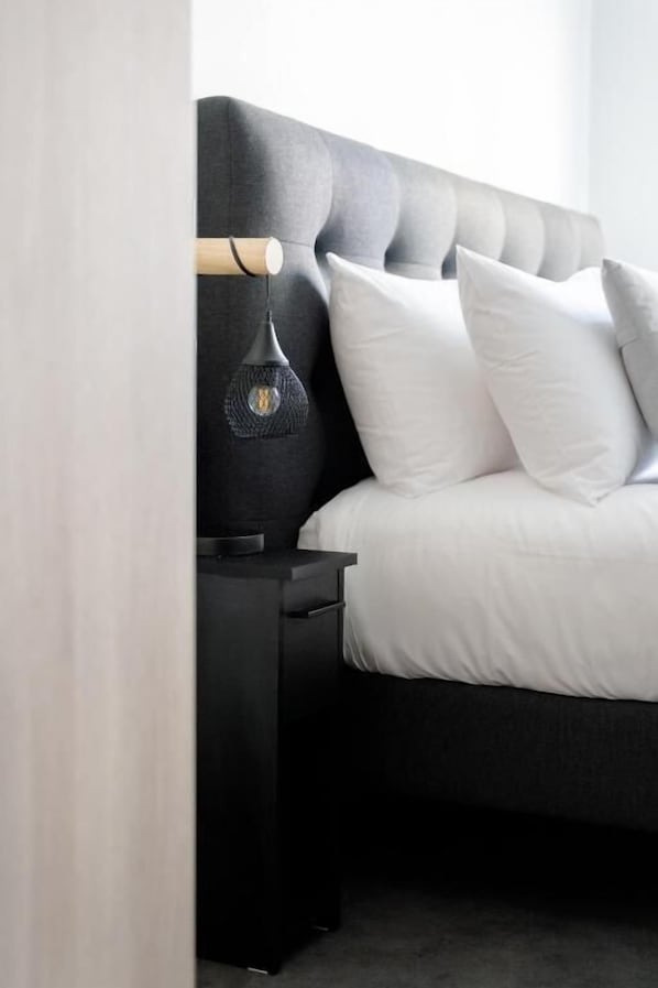 A bed with white bedding, a dark headboard, and a bedside lamp. - Slo Bordeaux Hostel (Bordeaux)