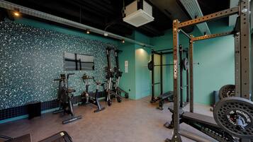 A gym with various exercise equipment, a television, and a green wall.