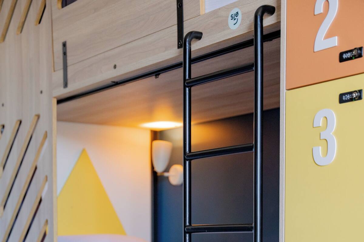 Un lit superposé avec une échelle, un bureau et des tiroirs de rangement, chacun étant marqué d’un numéro.