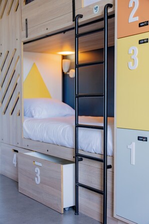 A bunk bed with a ladder, a desk, and storage drawers, each marked with numbers.