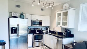 A modern kitchen with stainless steel appliances, white cabinetry, and a built-in microwave.