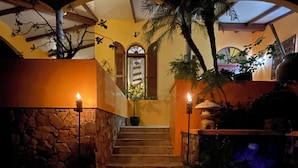 A staircase leading to a door with a small garden area on either side, featuring potted plants and a water feature. - The Polaris Pointe of St. Croix (Christiansted)