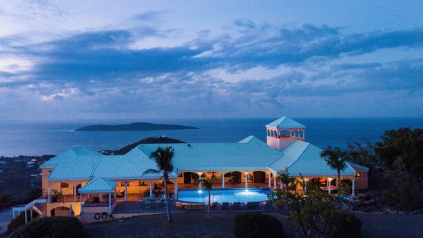 Een groot resort met een zwembad, meerdere gastenkamers en uitzicht op de oceaan.
