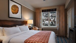 Een hotelkamer met een groot bed, een plafondventilator, een raam met gordijnen en een lijst met een foto aan de muur.