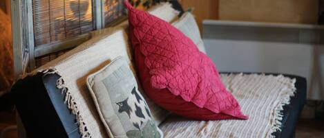 A sofa with a beige and black cushion, a red pillow, and a grey pillow with a star pattern.