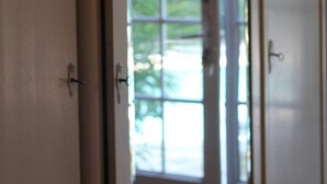 A room with a large window, a door with a decorative handle, and a wall with a floral pattern. - Gite Catalin à St Rémy de Provence (Saint-Rémy-de-Provence)