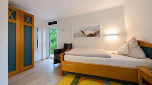 Un dormitorio con una cama, una silla, un escritorio y un armario.