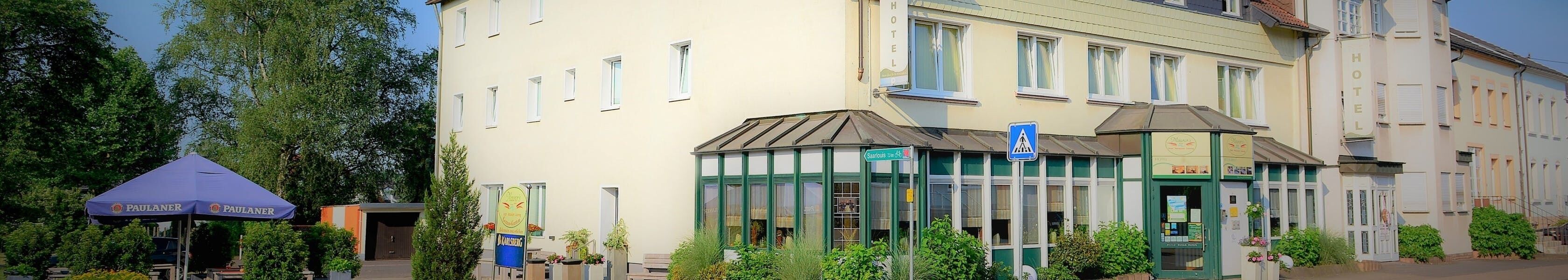 A hotel with a green facade, a visible entrance, and a sign indicating a restaurant.