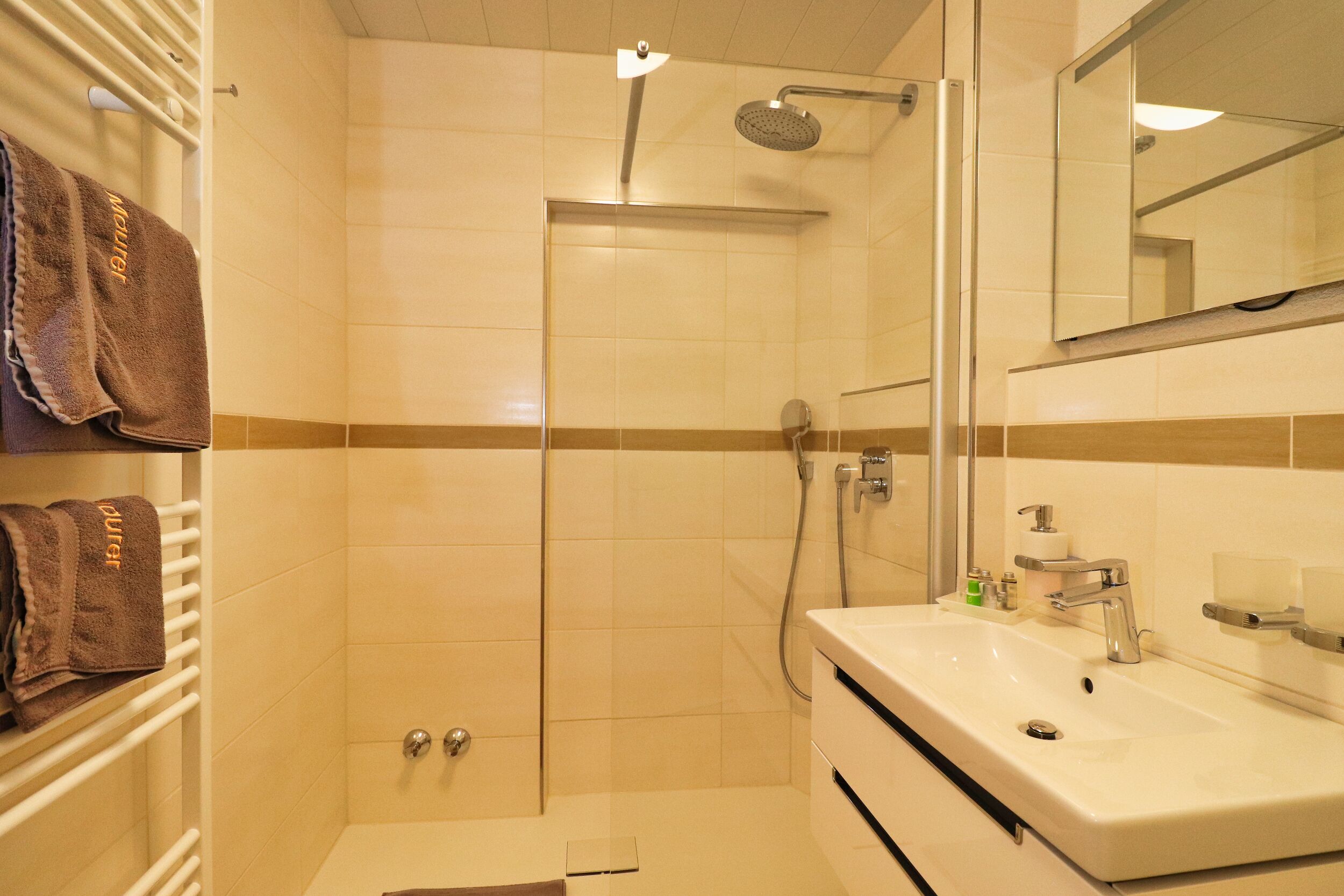 A bathroom with a shower, sink, and mirror.