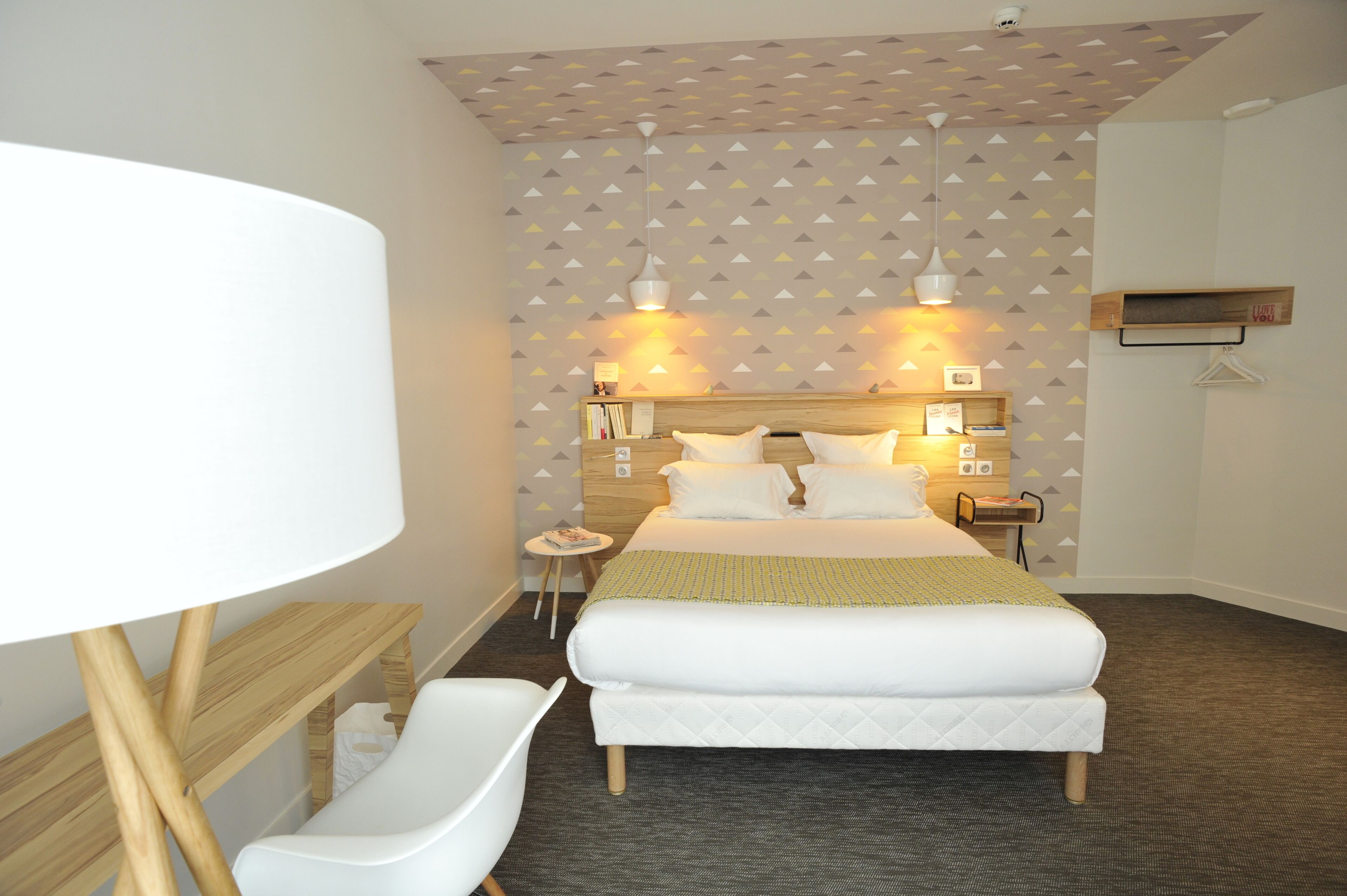 A neatly arranged hotel room with a bed, bedside tables, a chair, and a lamp.