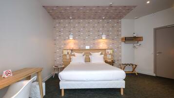 A neatly arranged hotel room with a bed, bedside tables, a desk, and a chair.