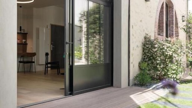 Une maison moderne dotée d’une grande porte-fenêtre coulissante qui donne sur un espace salle à manger.